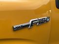 A close-up of the emblem on a 2014 Ford F-150 displaying the wording XL T and F 150 in chrome on a bright yellow surface