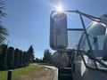 A 2004 Ford F-750 truck with a prominent side mirror reflecting sunlight and a round light below it