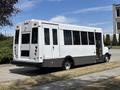 A white and black 2020 Chevrolet Express shuttle bus with large windows and a low floor design parked on the side of the street