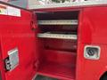 A red open storage compartment of a Chevrolet Silverado 3500HD featuring metal shelves and a handle for access with a locking mechanism on the door