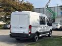 A white 2016 Ford Transit 150 van with a sliding side door and rear doors visible from the back angle