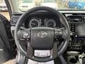 Steering wheel of a 2021 Toyota 4Runner featuring controls for audio and cruise settings with a prominent Toyota logo in the center