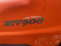 Close-up of a wet Kubota RTV 900 vehicle badge highlighting the words Power Steering and RTV 900 in silver on an orange surface