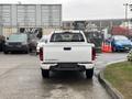 A white 2011 Chevrolet Colorado truck is parked with its tailgate facing forward showcasing the brand logo and model name on the back