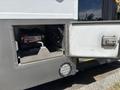 A 2020 Chevrolet Express showing a side compartment with a battery and a tool compartment door partially opened