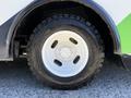 A close-up view of a white wheel with a rugged tire mounted on a 2013 Chevrolet Express