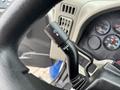 Close-up of a turn signal lever on a 2013 International DuraStar 4300 truck's steering column with dashboard gauges visible in the background