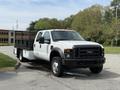 A 2008 Ford F-550 pickup truck in white with a black flatbed parked on a road