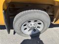 A close-up view of a tire and wheel of a 2013 Chevrolet Silverado 1500 with a silver rim and Chevrolet emblem on the wheel hub