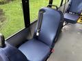 A navy blue seat with a safety belt inside a 2021 Ford Transit-350 bus with a modern design