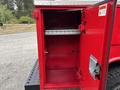 An open red utility box attached to a 2015 Chevrolet Silverado 3500HD showing metal shelves and a lockable door