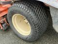Close-up of a large, rugged tire from a 2015 Kubota F3990 featuring deep treads and a cream-colored rim