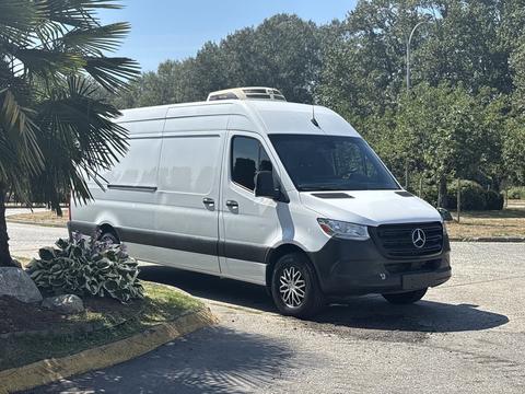 A 2019 Mercedes-Benz Sprinter van in white with a black front grille and silver wheels parked in a lot