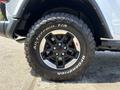 A close-up of a black wheel with a five-spoke design on a 2021 Jeep Wrangler showcasing an all-terrain tire with white lettering