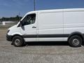 A 2016 Mercedes-Benz Sprinter van in white with a sliding side door and a plain side design parked on gravel