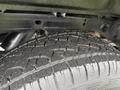 Close-up of a tire from a 2015 GMC Sierra 1500 showing a rugged tread pattern and some water droplets on the surface