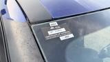 A blue 2019 Nissan Kicks with a visible windshield and a sticker indicating a certificate of approval for the vehicle