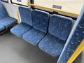 Three patterned blue seats in a public transit bus, with a modern design featuring a star-like pattern and equipped with handrails