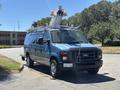 A blue 2008 Ford E-350 van equipped with a ladder rack and mounted equipment on the roof