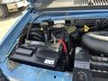 Close-up of the engine compartment of a 2005 Ford Econoline showing the car battery several hoses and engine components