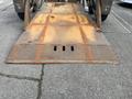 A metal loading ramp with a diamond plate surface showing signs of rust and wear featuring three rectangular openings near the bottom