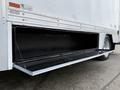 A silver storage compartment door on a 2012 Ford F-550 truck opens downward revealing a black interior space for cargo storage
