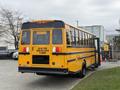 A 2022 Freightliner B2 school bus with a bright yellow exterior and black accents displaying a warning sign about red lights flashing on the back