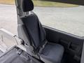 A single dark gray fabric seat with a seatbelt in a van interior designed for passenger seating
