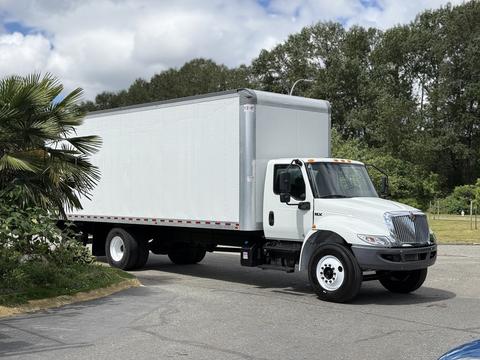 A 2022 International MV607 box truck with a white exterior and a large cargo area is parked with its front angled toward the viewer