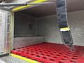 An empty storage compartment of a 1995 Freightliner FLL086 featuring a red grated floor and a black strap hanging down from the ceiling