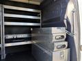 The interior of a 2023 Mercedes-Benz Sprinter 2500 featuring metal shelving and stacked storage boxes with handles