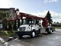 A white 2010 International 4300 truck equipped with a red lift and boom arm attached to the back