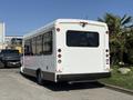 A white 2020 Chevrolet Express shuttle bus with multiple windows and taillights parked on a gravel surface