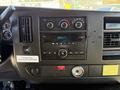 Dashboard of a 2014 Chevrolet Express featuring a radio, climate control knobs, various gauges, and a warning notice regarding vehicle operation