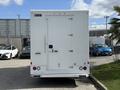 A white 2016 Ford Transit with a cargo box and double rear doors facing the viewer