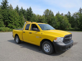 A yellow 2015 RAM 1500 pickup truck is parked with a cab and open bed showcasing a sturdy, utilitarian design