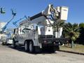 A 2013 International 7500 truck equipped with a hydraulic lift and utility body is parked in a lot