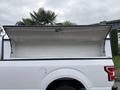 A white 2020 Ford F-150 truck with an open cargo cover showcasing an empty truck bed