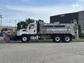A white 2013 Freightliner 114SD truck equipped with a dump bed and snowplow attachment parked on a street