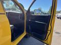 A yellow 2015 RAM 1500 with the driver's side door open showcasing the interior features and dashboard