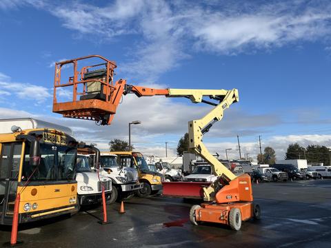 A 2012 JLG E400AJFN aerial lift with an orange platform extended upwards attached to a yellow arm in an industrial setting