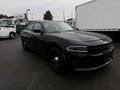 A black 2017 Dodge Charger with a sleek design and black wheels parked on a surface with rain droplets visible on its surface