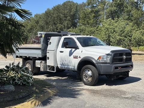 A 2016 RAM 5500 work truck with a flatbed and toolboxes on the side parked on a driveway