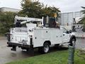 A 2018 Ford F-550 service truck with a white body and equipment including a crane, generator, and tool compartments mounted in the bed