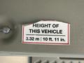 A label inside a vehicle indicating the height of the 2017 Chevrolet Express as 3.32 m or 10 ft 11 in