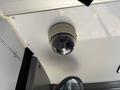 A circular black surveillance camera mounted on a white ceiling inside a vehicle