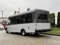 A 2020 Chevrolet Express bus with a white exterior and large windows parked on a wet surface