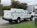 A white 2015 Ford F-350 SD truck with a utility service body and multiple storage compartments on the sides