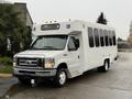 A white 2017 Ford E450 bus with a large front windshield and multiple side windows designed for transporting passengers with accessibility features