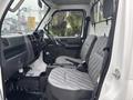 Interior of a 2010 Suzuki Carry featuring two gray upholstered seats and a dashboard with controls and storage compartments